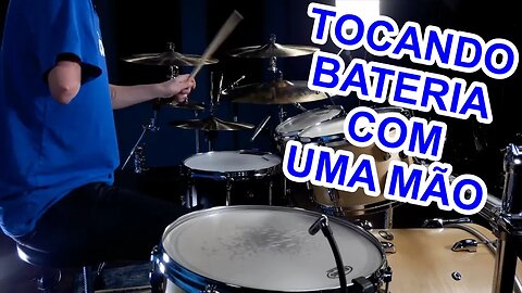 Homem tocando bateria com uma mão.