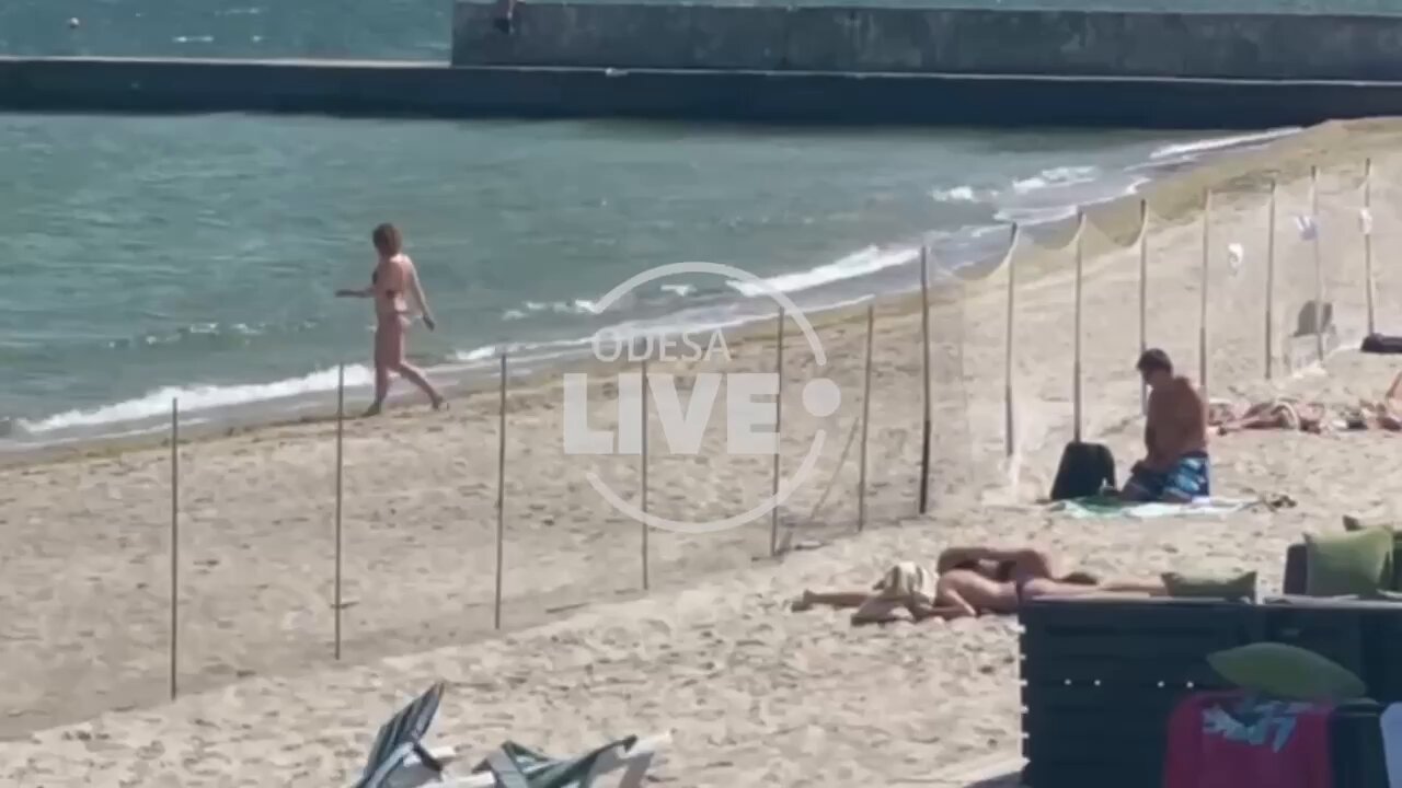 Woman at beach in Odessa ignores fence put up because of Ukrainian mines