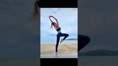 Czarina Irena practicing beachside yoga in black leggings with a blue waistband