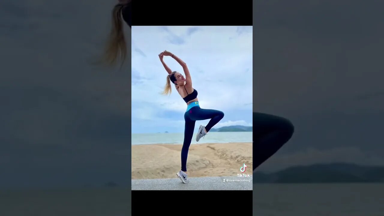 Czarina Irena practicing beachside yoga in black leggings with a blue waistband