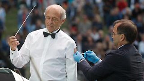 A conductor receives a "vaccine" on stage... because "SHOW MUST GO ON" he says