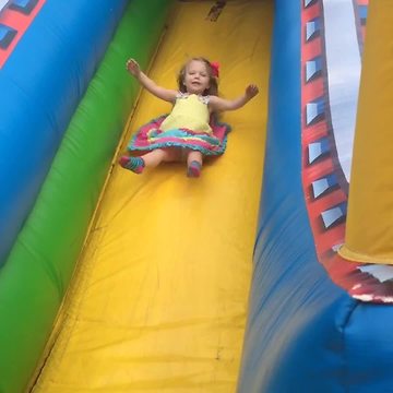 "Tot Girl Rides Down An Inflatable Bounce Slide And Her Dress Flies Up"