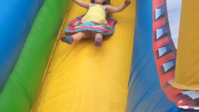 "Tot Girl Rides Down An Inflatable Bounce Slide And Her Dress Flies Up"