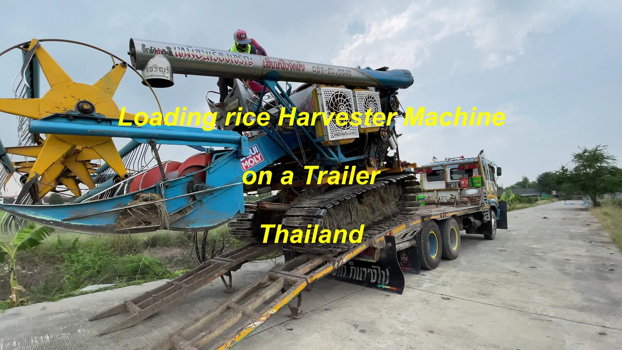 Loading rice harvester machine on a trailer in Thailand