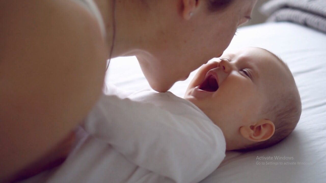 Mother-kissing-her-cute-baby-girl-on-bed.