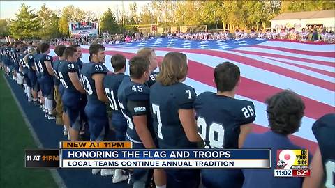 Rival high school teams hold giant U.S. flag together