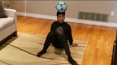 Boy balances ball on the head like a pro