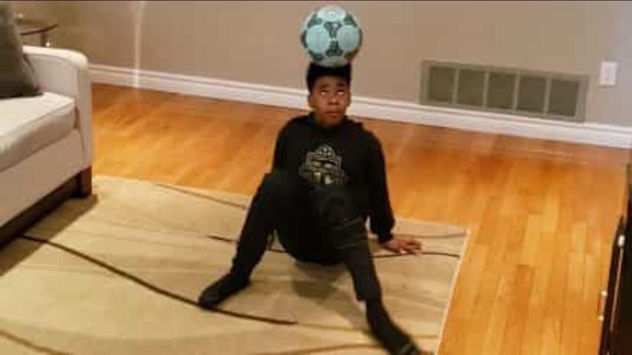 Boy balances ball on the head like a pro