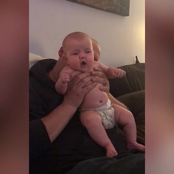 "Baby Girl Makes Surprised Face When Dad Blows Raspberries on Her Back"