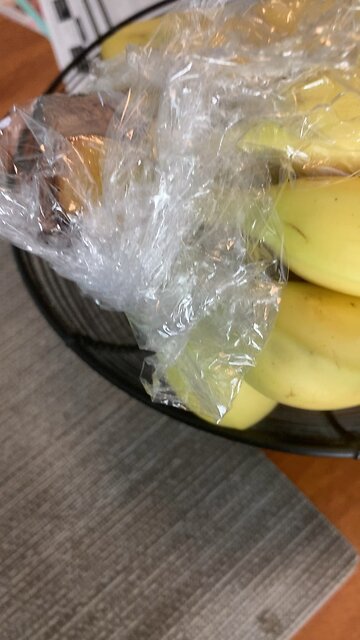 Wrapping banana stems in cling wrap for freshness