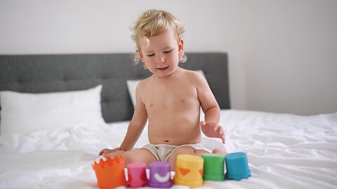 Kid Playing with his Toy Cups on Bed