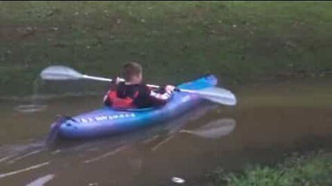 Rapaz diverte-se a andar de caiaque em rua inundada