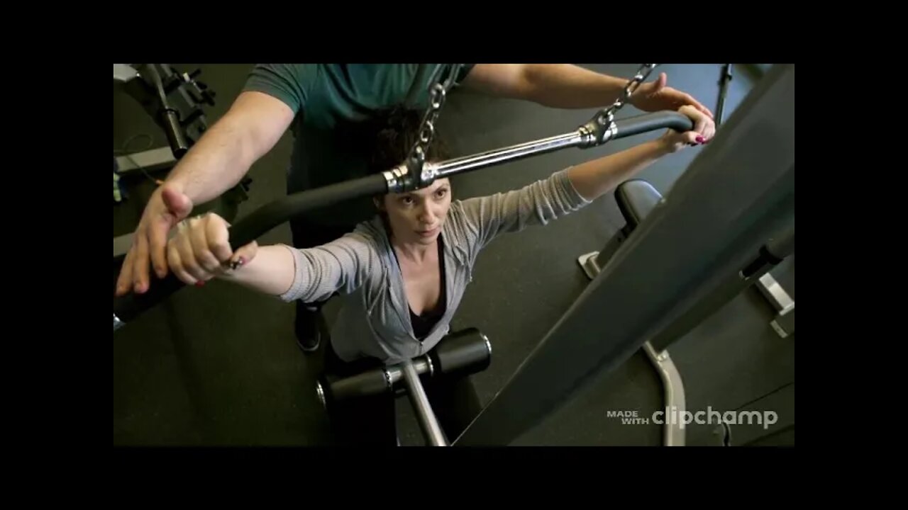 A Man Assisting A Woman In Using The Flat Pulldown Weights Equipment In A Gym