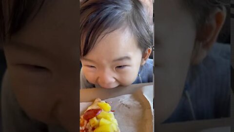 Hungry toddler chews the box while waiting for pizza to cool