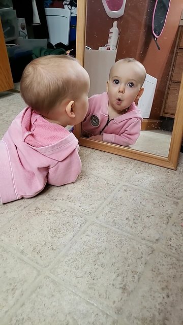 Adorable baby befriends her reflection in the mirror