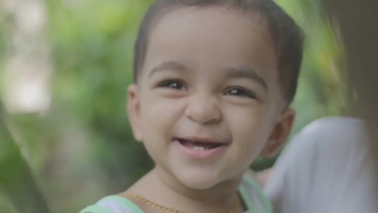A year old baby, smiling with a gentle smile from showing whiter teeth.