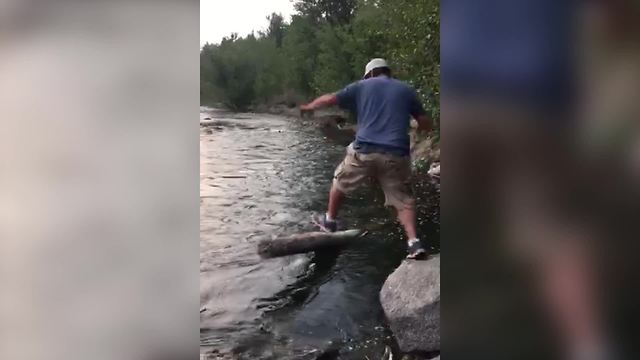 Man Jumps From A Rock To A Log In A River