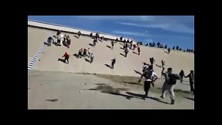 Migrants run through canal toward border