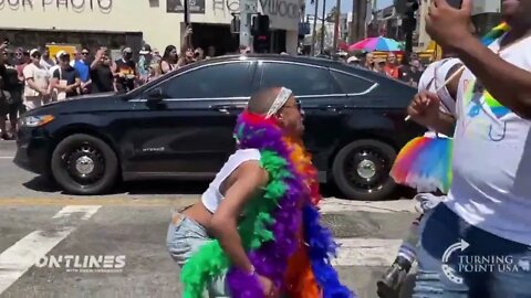 A woman forces a boy against his will to watch the LA PRIDE March as LGBTQ attendees twerk