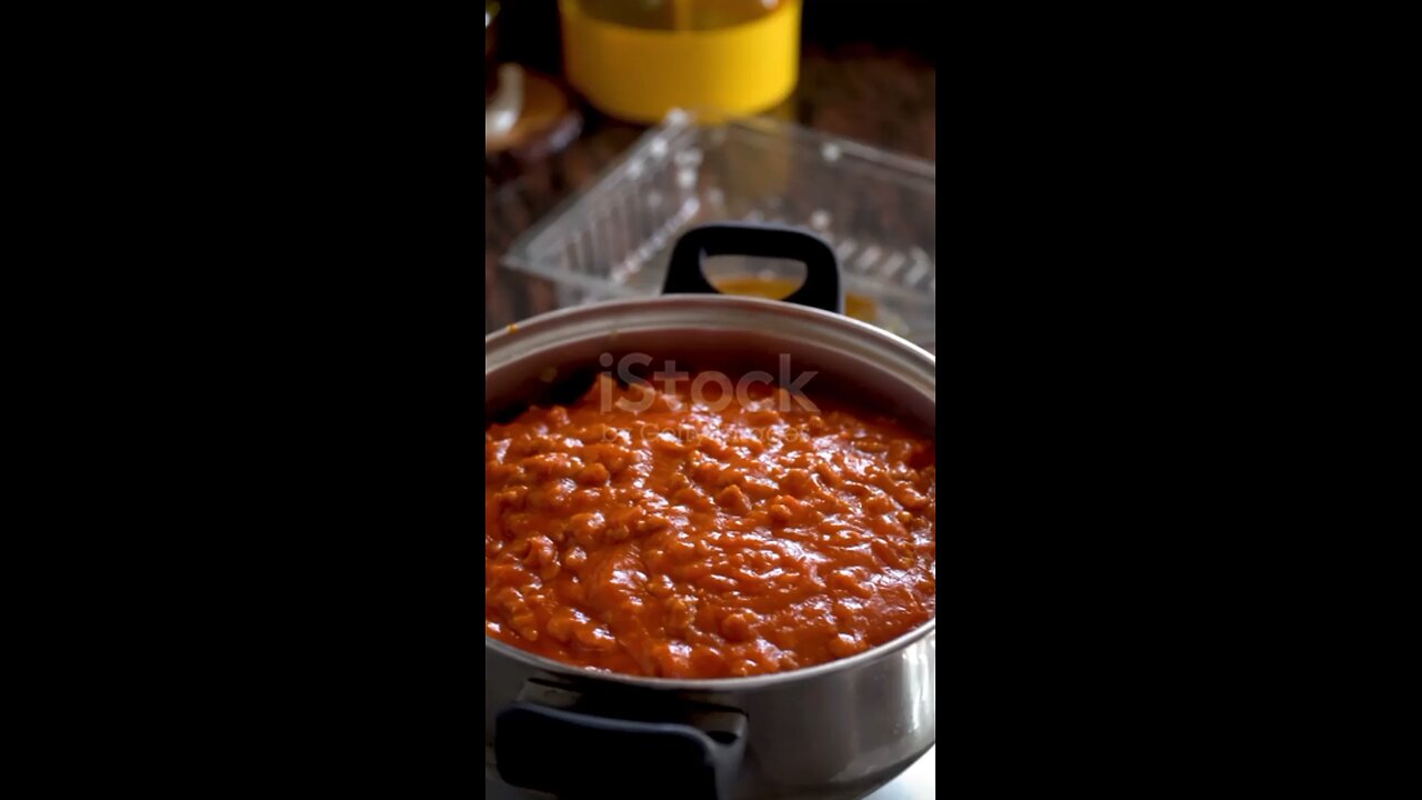 closeup, a person adds the bolognese sauce to a pot with cooked macaroni