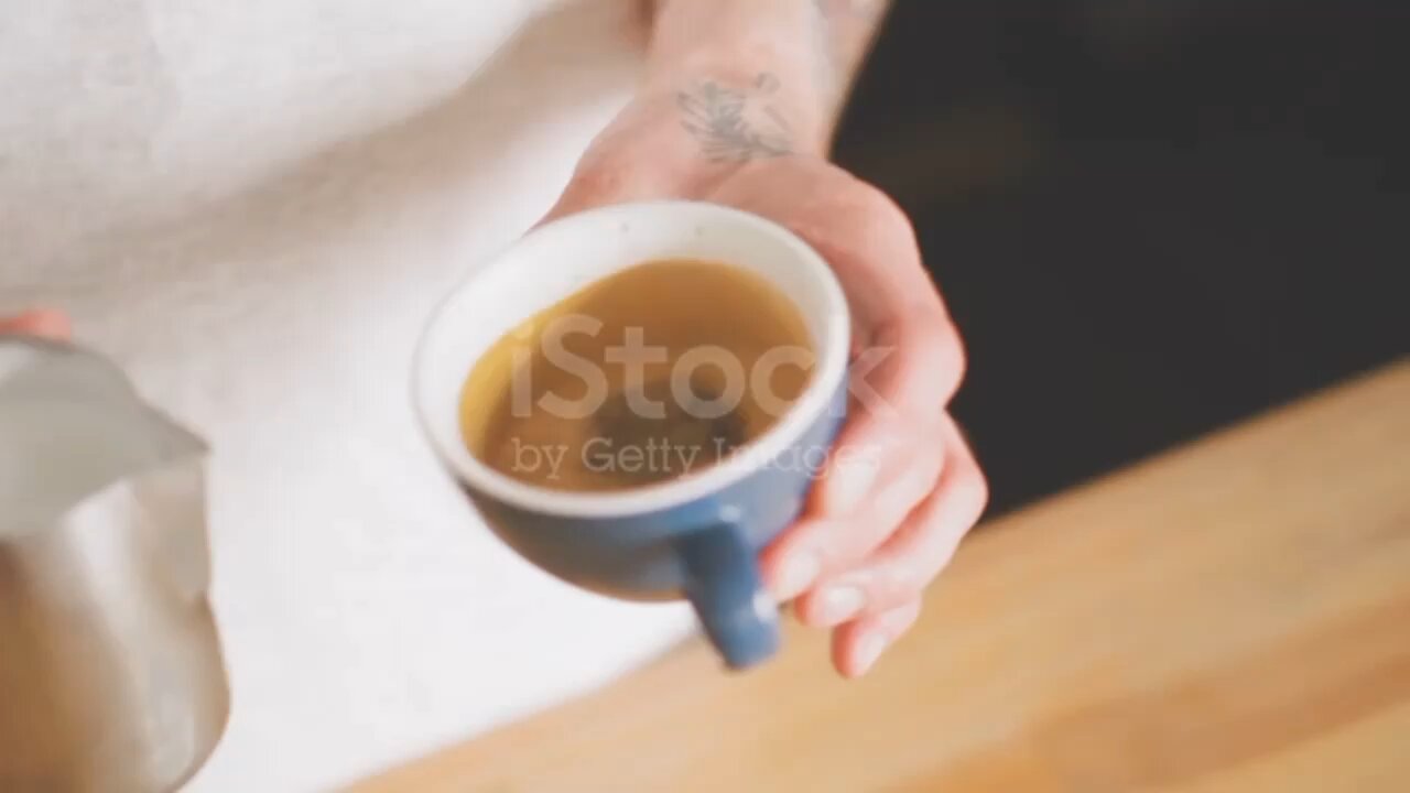 Close up of a barista that is creating some beautiful latte art with steamed milk and espresso.