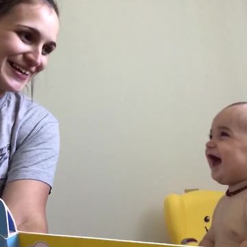 A Baby Girl Laughs Out Loud At A Book About Animals