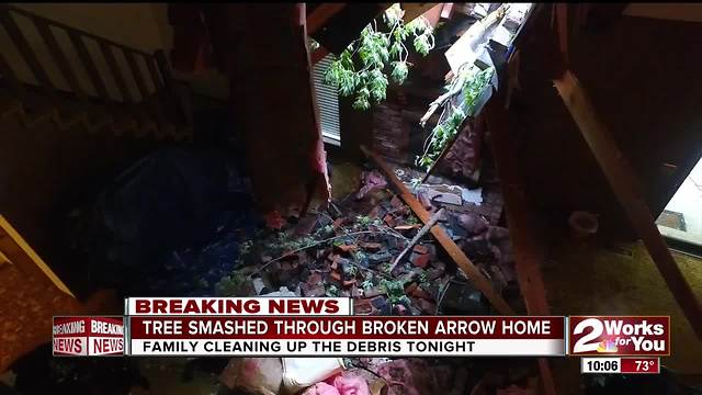 A tree goes through a Broken Arrow woman's home as a tornado rips through Green Country