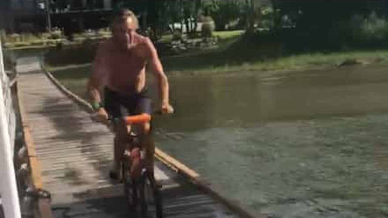 Guy performs epic lakeside bicycle jump