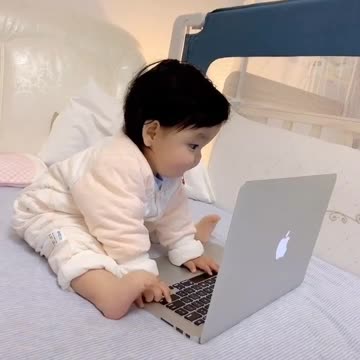 a cute little baby play with laptop moving his feet