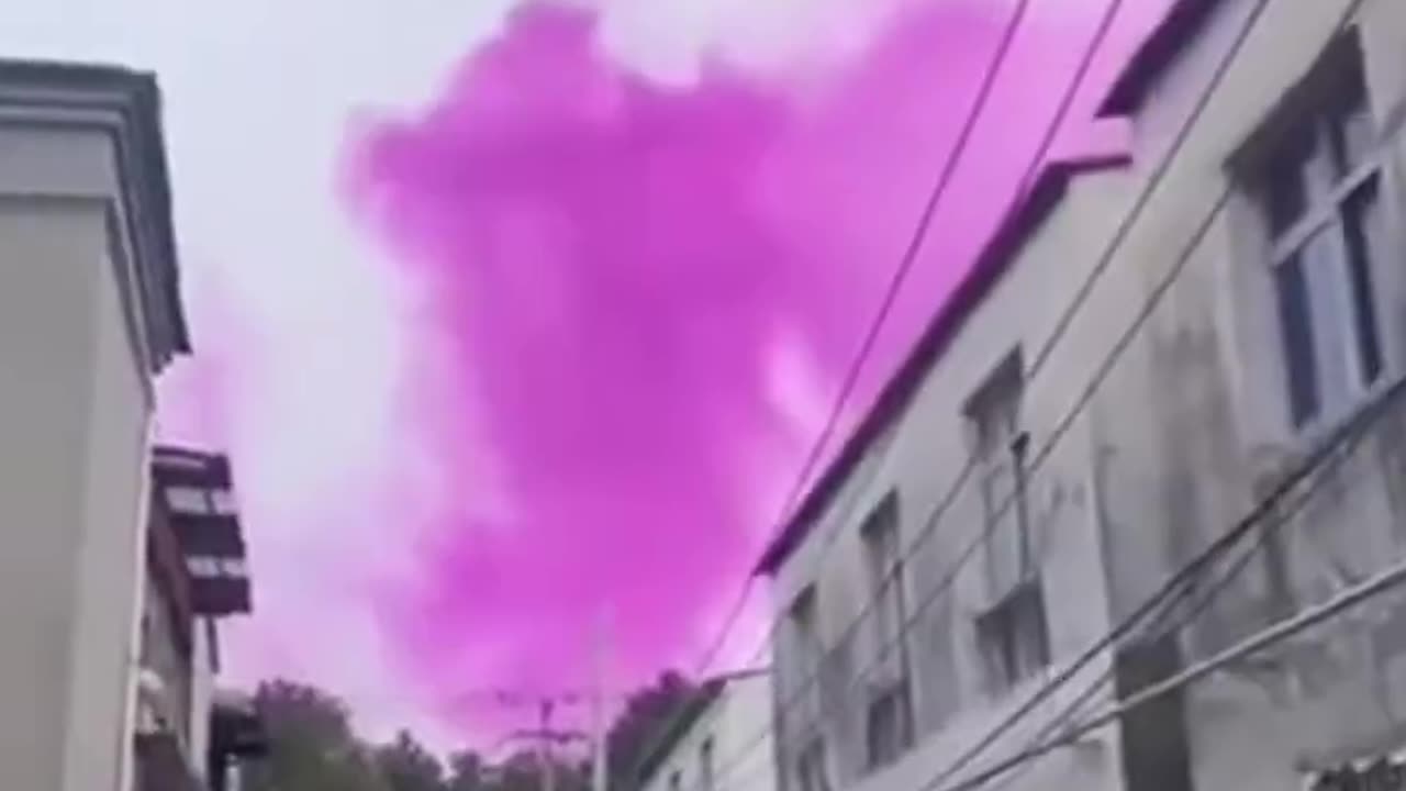 Purple smoke rises from factory chimney