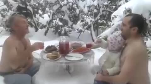 The men eat their lunch in the snow