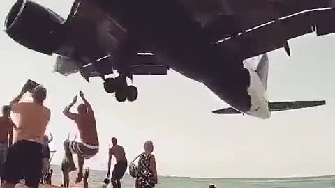 The plane flies over the beach