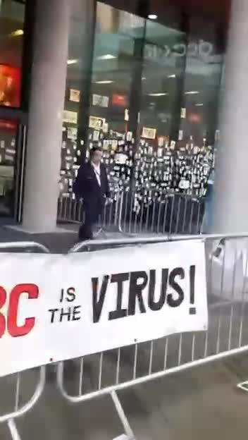 BBC news studio windows being plastered with stickers, posters, and pictures of loved ones believed to be injured or killed by the Covid-19 vaccine.