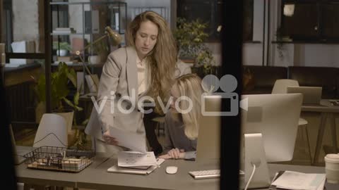 Two Female Employees Talking Together And Checking Reports In The Office