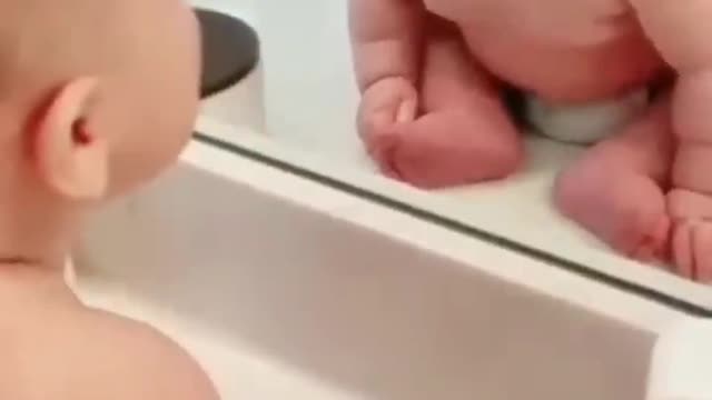 The baby looks at himself in the mirror and smiling😊🤣