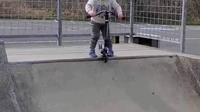 Toddler Imitates Dad's Pre-Run Warm-Up Ritual Before Sliding Down Ramp on Scooter