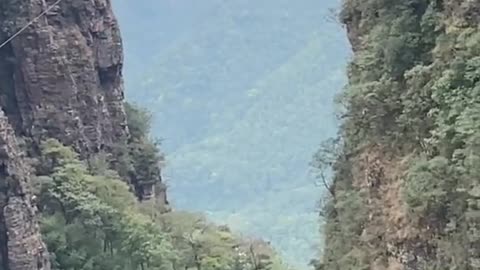 Adventure driving motorcycle on rope between mountains