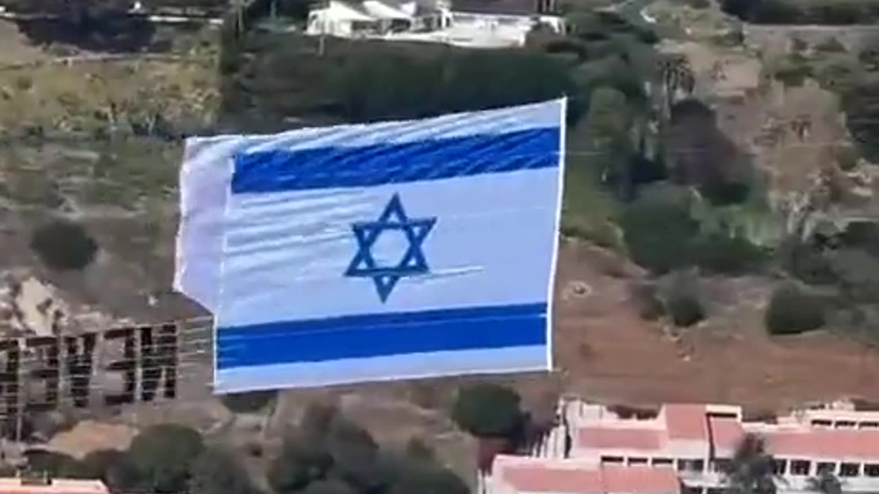 An Israeli flag with the slogan “Never Again” is towed over Hollywood.