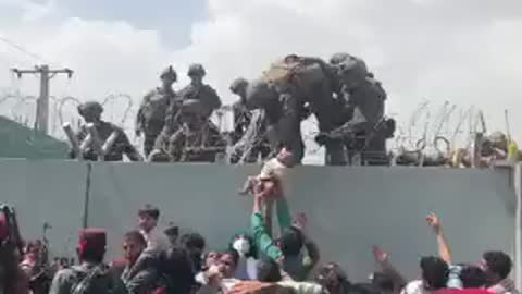 NEW - Toddler pulled over wall by U.S. soldiers as desperate crowds gather outside Kabul airport.