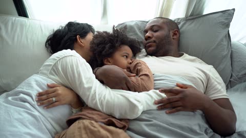 A Family Of Three Resting On The Bed