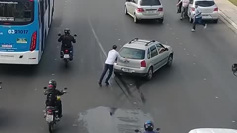 A kind stranger assists in pushing a stalled car off the highway.