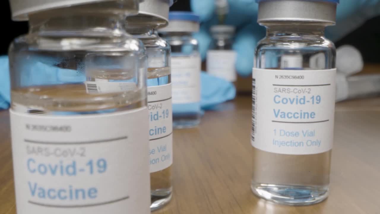 Sliding Shot Past Covid Vaccine Vials and Syringes to Close Up of Single Vial