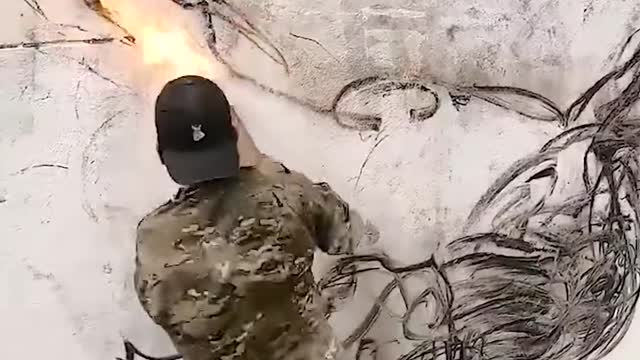 Guy uses a burning stick to draw on the wall