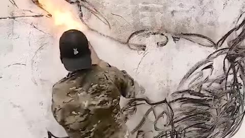 Guy uses a burning stick to draw on the wall