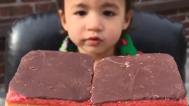 Toddler eating chocolate-topped rainbow cookies