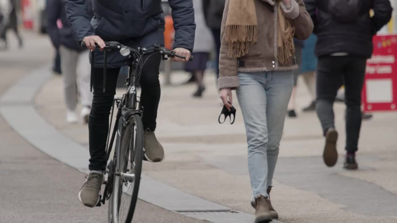 Long Shot of Cyclist and People Walking Down Queen Street In Oxford England