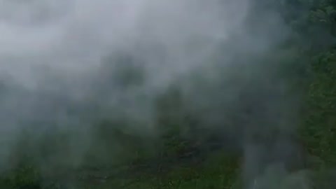 A waterfall cascades down the cliff from the hills behind.