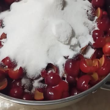 Adding sugar to cherry plums for jam