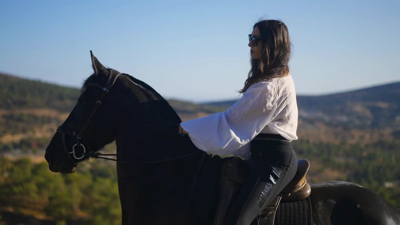 Side view of gorgeous confident equestrian in sunglasses sitting