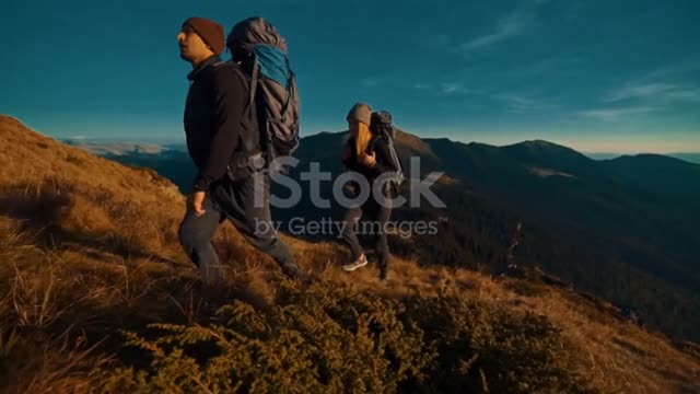 The Couple With Camping Backpacks Walking To The Mountain